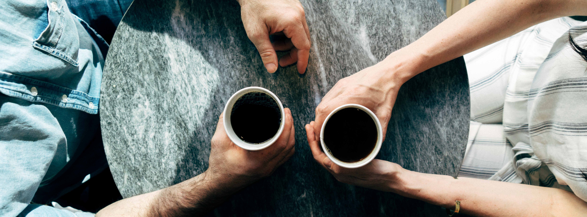 Two men with cups of coffee having a mock professional diiscussion